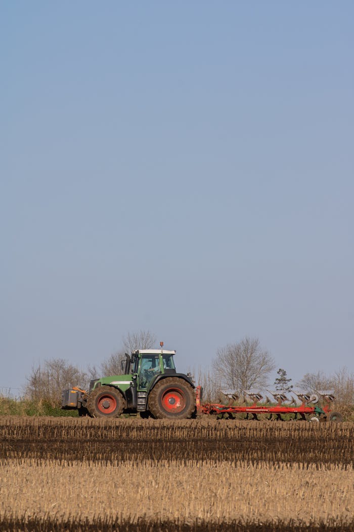services-01 Green tractor plowing a rural field, representing agricultural work and landscape.
